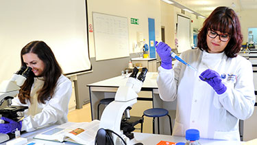 Female students working in a medical science lab wearing lab coats